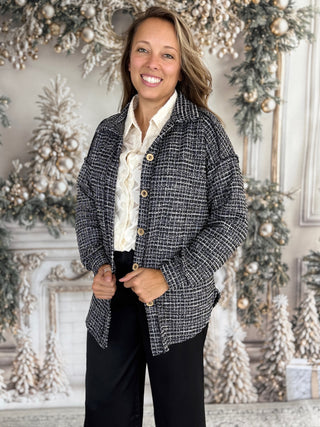 Woman wearing a patterned jacket in a decorated room with Christmas trees.