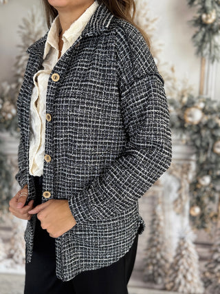 Person wearing a black and white checkered jacket with a blurred decorative background