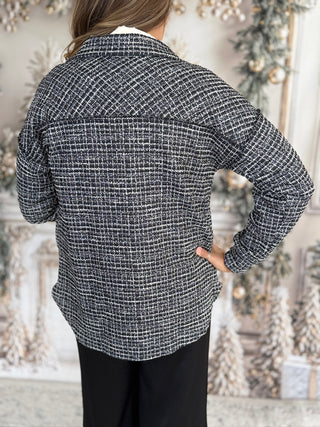 Person wearing a black and white checkered shirt with a blurred decorative background