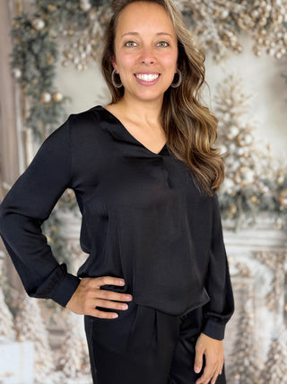 Woman wearing a black long-sleeve top with a decorative background