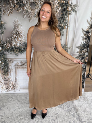 Woman wearing a brown dress in a decorated room with Christmas trees.