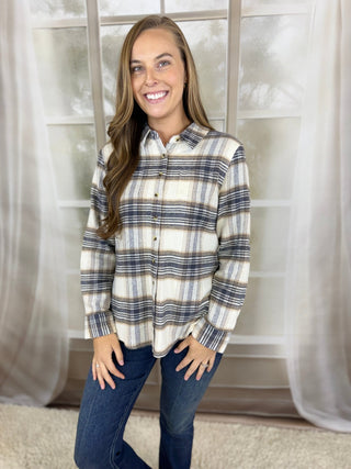 Woman in a cream and navy plaid flannel button-up with jeans | V-Rae's Boutique