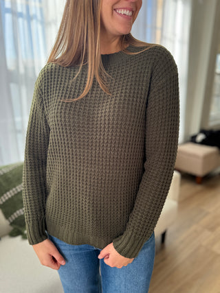 Woman wearing a green knitted sweater in a living room setting