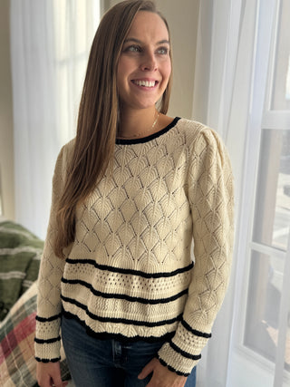 Woman wearing a beige sweater with black stripes indoors