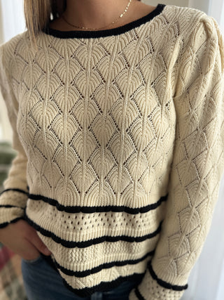 Beige sweater with black ribbed trim worn by a person