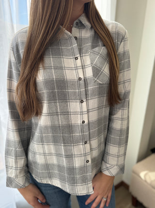 Person wearing a gray and white plaid shirt with a blurred background