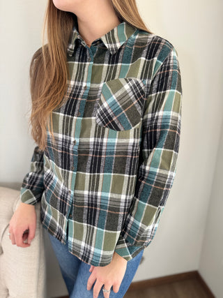 Person wearing a plaid shirt with green, black, and white pattern.
