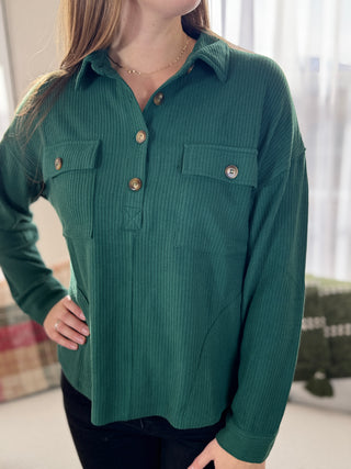 Green ribbed shirt worn by a person indoors