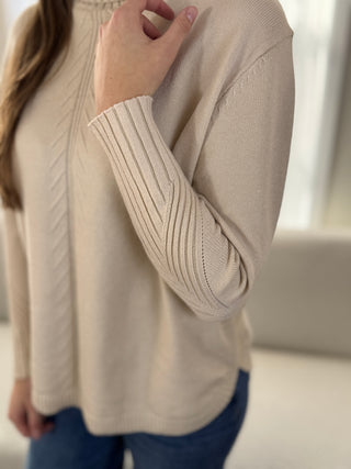 Beige sweater worn by a person with a blurred background