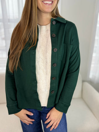 Person wearing a green jacket over a white shirt with a blurred background