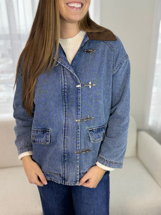 Person wearing a blue denim jacket with a neutral background