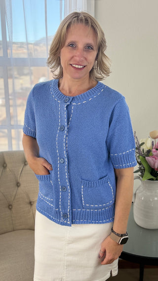Woman wearing a blue knitted cardigan in a living room setting