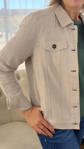 Person wearing a beige denim jacket with a blurred background