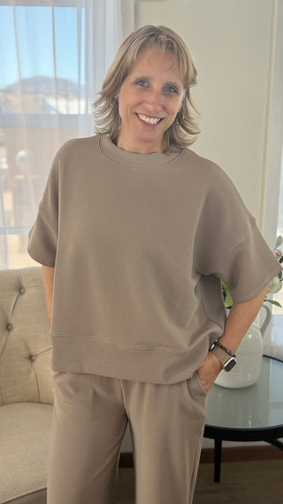 Woman wearing a beige outfit standing in a living room.
