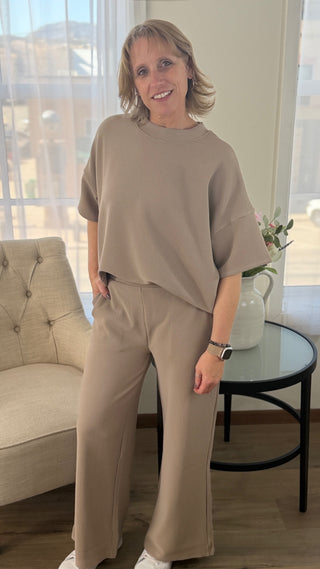 Woman wearing a beige outfit standing in a living room.