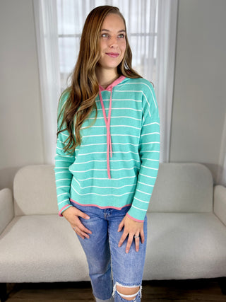 Photo of a woman in a mint sweater with pink trim.