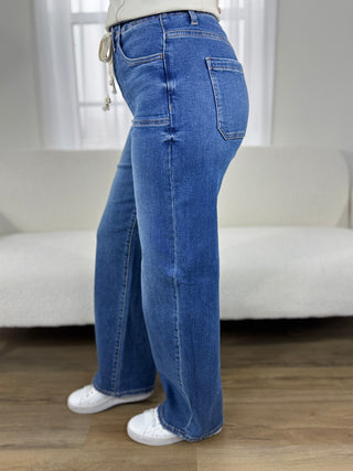 Person wearing blue jeans and white sneakers in a room with a white couch and light-colored walls.