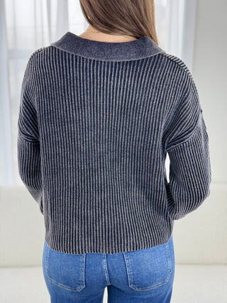 Person wearing a striped sweater and blue jeans against a white background