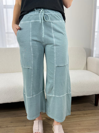 Person wearing light blue pants with a drawstring waist in a room with a white couch.