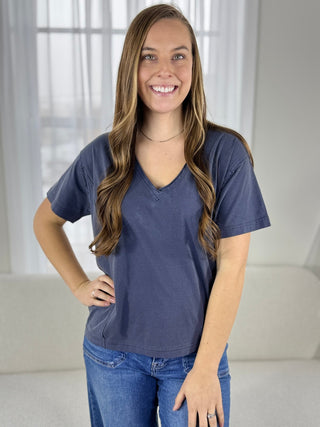 Woman wearing a blue t-shirt and jeans indoors with a neutral background