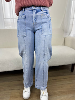 Person wearing light blue jeans and white sneakers in a room with a beige sofa.