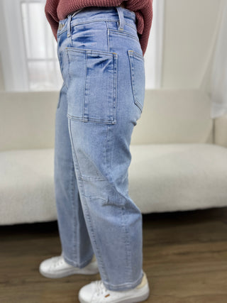 Person wearing light blue jeans and white sneakers in a minimal indoor setting