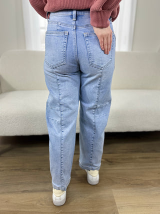 Person wearing light blue jeans and a pink sweater in a room with a beige sofa.