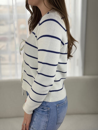 Person wearing a white and blue striped sweater with a neutral background