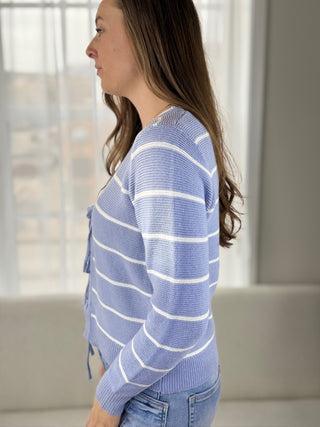 Woman wearing a blue striped sweater in a neutral indoor setting