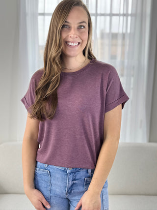Woman wearing a purple t-shirt and blue jeans indoors