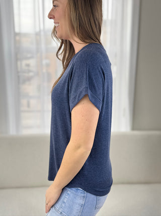 Woman wearing a blue t-shirt and jeans in a neutral setting