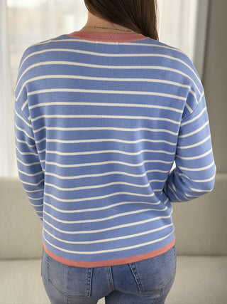 Person wearing a blue and white striped sweater with a neutral background