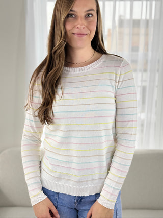 Woman wearing a striped sweater with pastel colors in a neutral setting