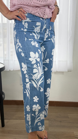 Blue jeans with white floral patterns worn by a person indoors.