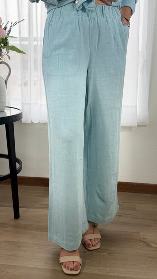 Person wearing light blue pants standing indoors with a blurred background