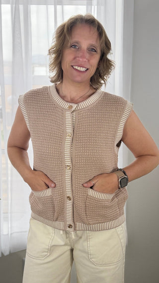 Woman wearing a beige knitted vest with a plain background