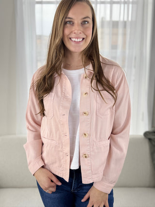 Woman wearing a pink jacket indoors with a neutral background