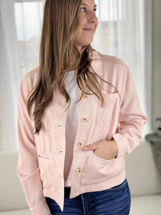 Woman wearing a light pink jacket indoors with a neutral background
