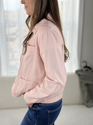 Woman wearing a light pink jacket in a neutral indoor setting