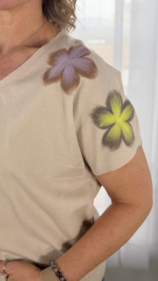 Beige sweater with floral designs on a plain background