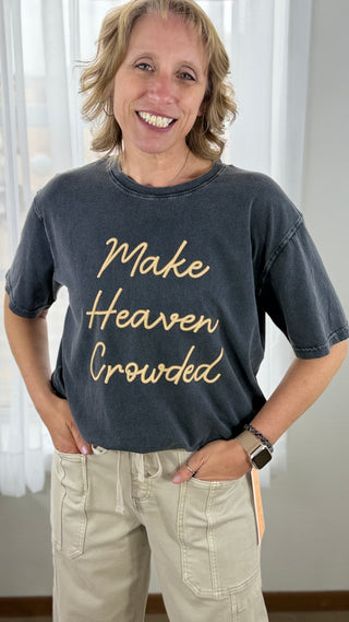 Person wearing a dark blue t-shirt with 'Make Heaven Crowded' text, standing indoors.