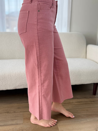 Person wearing pink pants standing in a room with a couch and wooden floor.