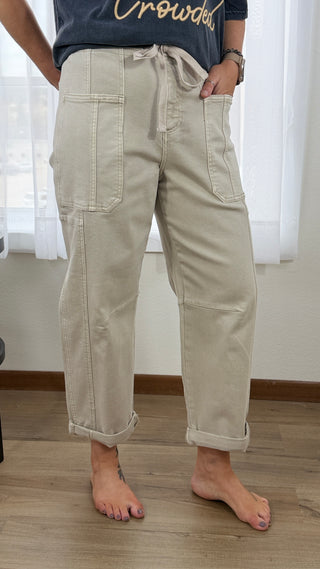 Person wearing beige cargo pants standing indoors with a neutral background