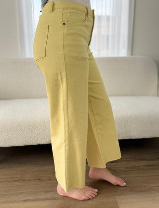 Person wearing yellow pants standing in a room with a couch and window in the background.