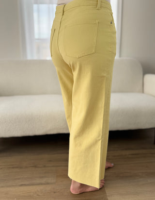 Person wearing yellow pants standing in a room with a white couch.