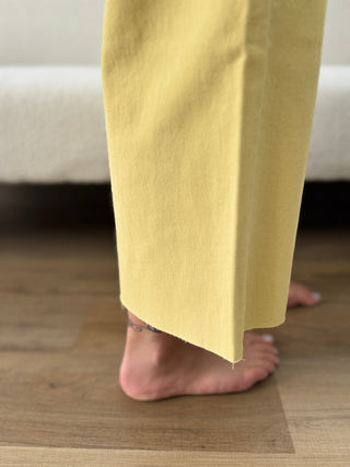 Yellow pants being worn on a wooden floor with a blurred background