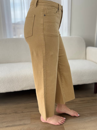 Person wearing beige pants standing in a room with a white couch and light-colored walls.
