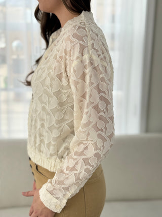 Person wearing a white lace blouse with a blurred background