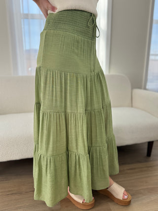 Person wearing a green tiered skirt in a room with a white couch.