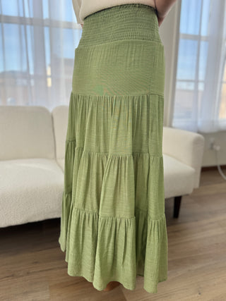 Green tiered skirt worn by a person in a room with a couch and window.